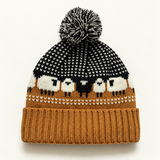 Black Camel sheep-pattern Fair Isle pom-pom beanie on a clean warm-white background