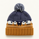 Midnight Mustard sheep-pattern Fair Isle pom-pom beanie on a clean warm-white background